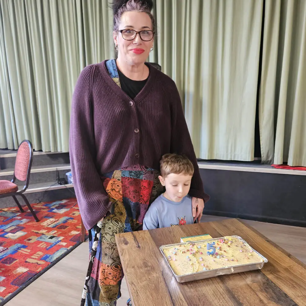 A young boy getting ready to blow out the candle on his 5th birthday cake at a Music and Mayhem children's party.