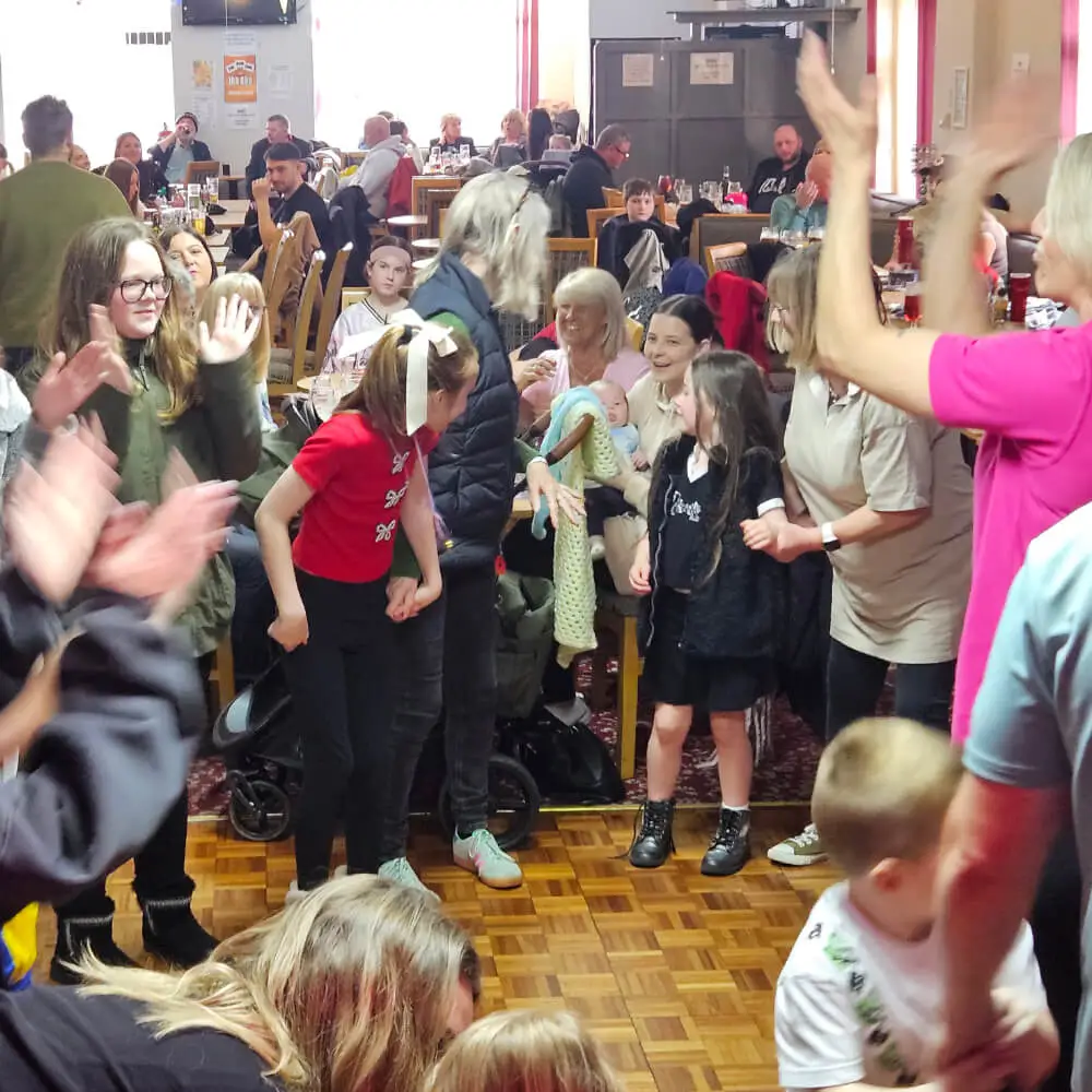 Families and children clapping and dancing on the dance floor at a busy Easter party hosted by Music and Mayhem.