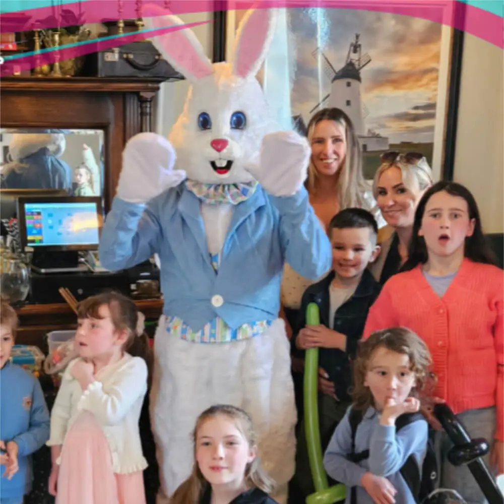 Music and Mayhem children's entertainer in an Easter Bunny mascot costume posing with families at an Easter party event.