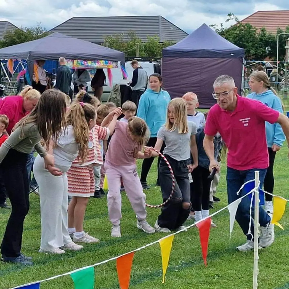 Children's entertainer from Music & Mayhem organizing outdoor party games and activities with a group of kids at the Warton Carnival in Lancashire.